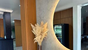 A reception area with a marble wall, wooden accents, and a vase with dried pampas grass. - Portal Parque Hotel (Francisco Beltrao)