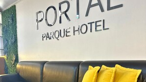 A black leather sofa with three yellow pillows in a hotel lobby with a 'PORTAL PARQUE HOTEL' sign on the wall. - Portal Parque Hotel (Francisco Beltrao)