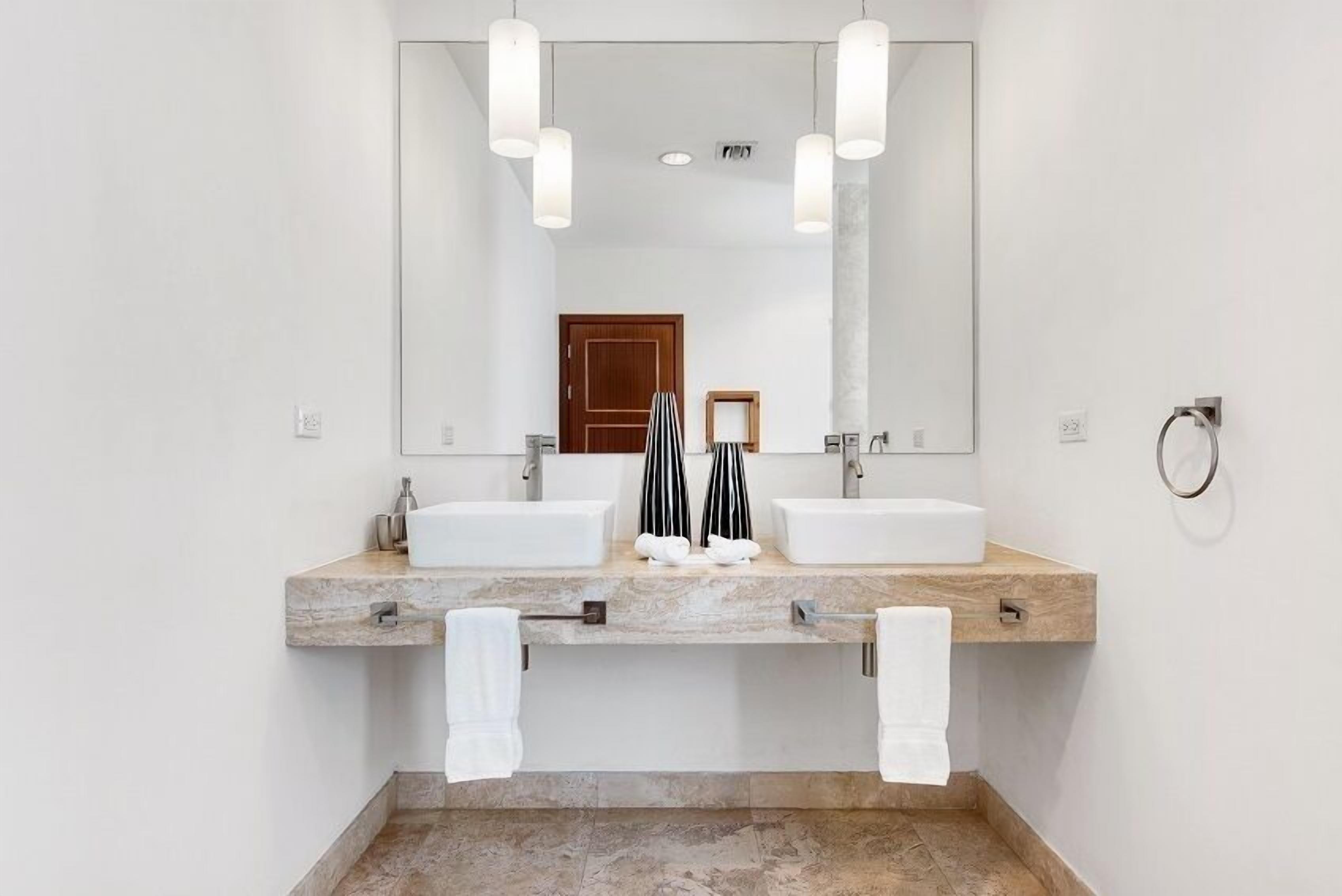 Un baño moderno con dos lavamanos, un espejo grande y un perchero para toallas.