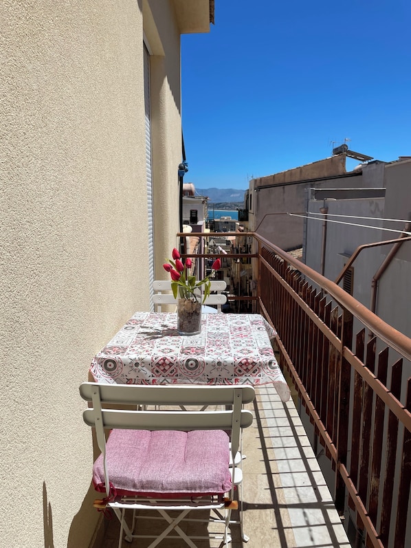 A balcony with a table, chairs, and a vase of flowers.