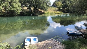 Un río tranquilo con barcos amarrados en un muelle de madera, rodeado de vegetación exuberante.