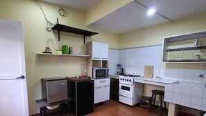 A compact kitchen with a refrigerator, microwave, stove, and a small sink. - Cozy room with private bathroom and access to kitchen with terrace in Miraflores (Lima)