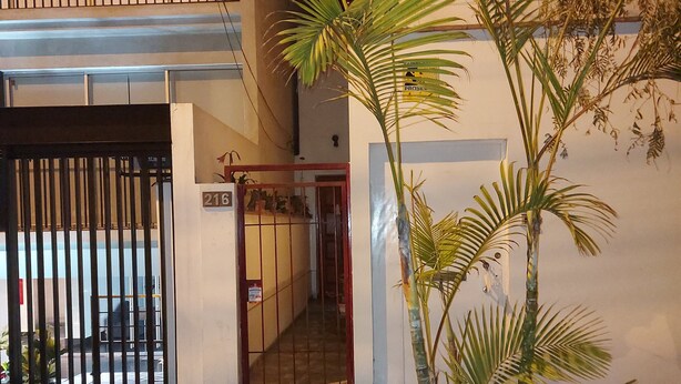 A gated entrance with a number sign, a palm tree, and a building with a balcony. - Cozy room with private bathroom and access to kitchen with terrace in Miraflores (Lima)