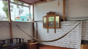 A room with a tiled floor, a wooden bench, a table with a patterned tablecloth, a hanging light fixture, and a wall-mounted mirror. - Cozy room with private bathroom and access to kitchen with terrace in Miraflores (Lima)