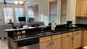 A modern kitchen with wooden cabinets, a stainless steel dishwasher, and a black countertop. - Steinhatchee Landing Resort-Serendipity #48-Dog Friendly-**THIRD NIGHT FREE** (Steinhatchee)