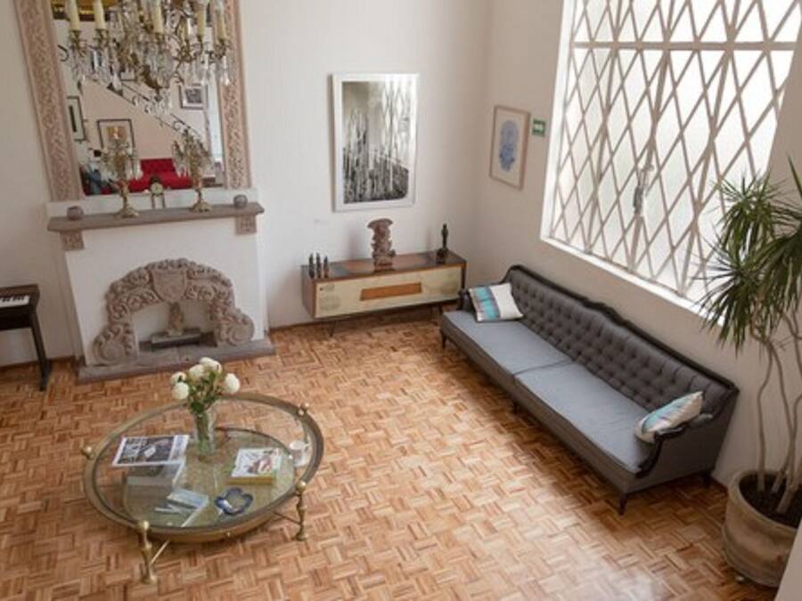 Una sala de estar con sofá, una mesa de centro de vidrio, chimenea y piano.