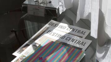 A glass table with a newspaper, a tissue box, and a striped bag on it.