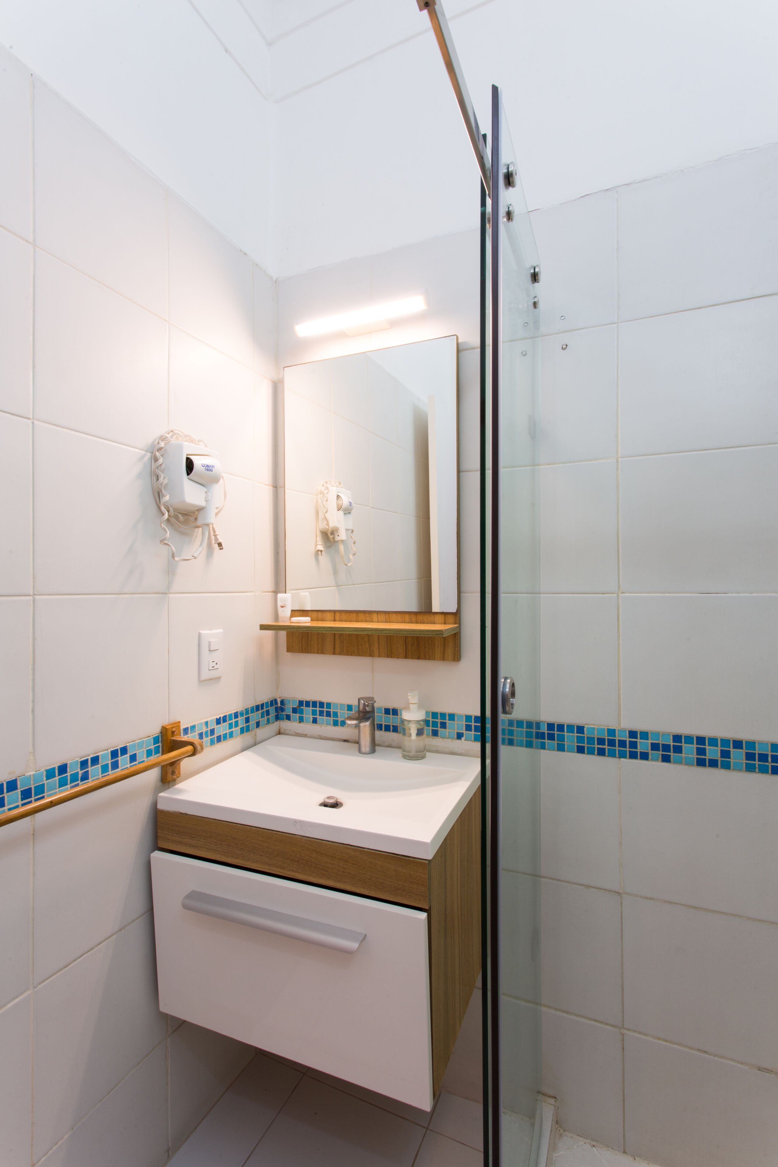 A bathroom with a glass shower enclosure, a white sink with a wooden countertop, and a mirror above the sink.