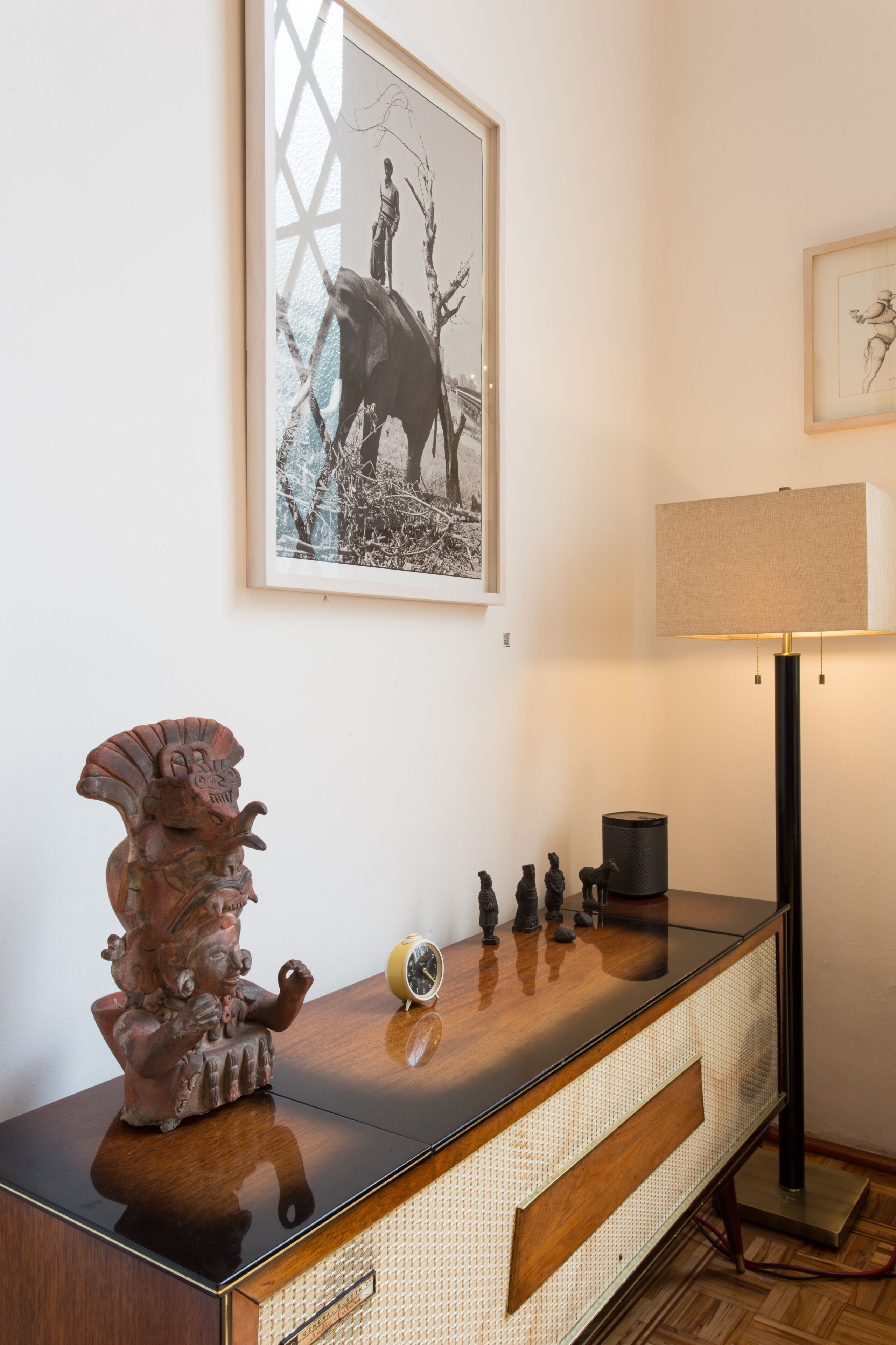 Et værelse med et trækonsolbord, en lampe, et billedramme og et lille ur.