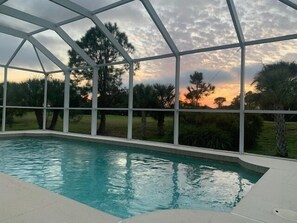 An indoor swimming pool with a view of trees and a sunset through a glass enclosure. - * Your Peaceful Florida Escape Awaits! * (Rotonda West)