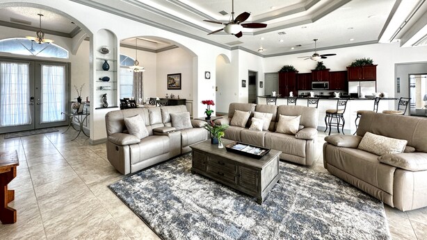 A spacious living room with a large sectional sofa, a coffee table, and a dining area with chairs.