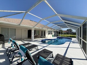 An outdoor pool area with a covered patio, lounge chairs, and a dining table. - Near many golf courses, delicious local restaurants, and unforgettable adventures! (Rotonda West)