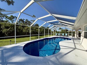 A covered swimming pool with a curved edge, surrounded by a white metal frame and a glass canopy. - Near many golf courses, delicious local restaurants, and unforgettable adventures! (Rotonda West)