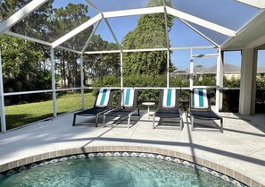 Una piscina scoperta coperta con lettini e un tavolino.
