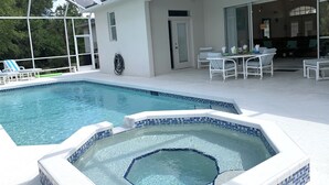 Ein Pool mit Whirlpool, Sitzgelegenheiten im Freien und einer überdachten Terrasse.