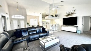 Ein modernes Wohnzimmer mit einem Ecksofa, einem Couchtisch und einem Flachbildfernseher.