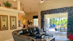 A spacious living room with a leather sofa, a coffee table, and a dining area with a view of the outdoors.