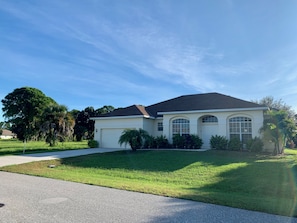 A single-story house with a garage, surrounded by a well-maintained lawn and trees.