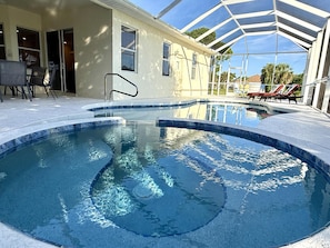 Una piscina con una fuente de agua azul cristalina, rodeada por un área de patio techada con sillas de descanso.