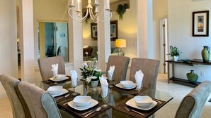Un coin repas avec une table en verre, dressée pour quatre personnes, entourée de chaises rembourrées.