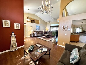 A spacious living room with a wooden floor, a sofa, a coffee table with magazines, a chandelier, and a view to the kitchen. - * Waterfront home to relax, reconnect, and create unforgettable memories together! * (Port Charlotte)