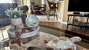 Ein Wohnzimmer mit einem Glastisch, der eine Dekoterrasse, ein gewebtes Seil und eine Perlenkette zeigt.