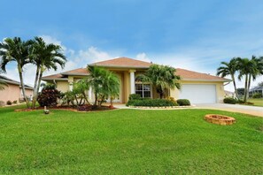 A single-story house with a tiled roof, a front garage, and a well-maintained lawn with palm trees. - * Waterfront home to relax, reconnect, and create unforgettable memories together! * (Port Charlotte)