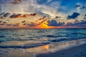 A beach with waves and a sunset.