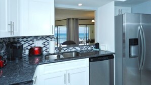 A modern kitchen with white cabinets, a stainless steel refrigerator, a coffee maker, and a water dispenser.