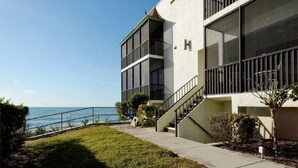 A modern building with a staircase leading to a balcony overlooking the sea.