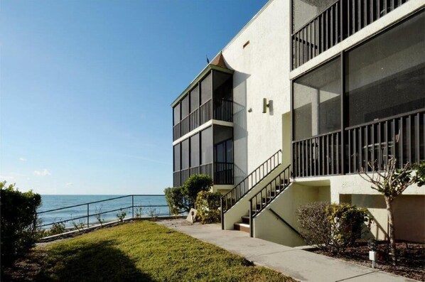 A modern building with a staircase leading to a balcony overlooking the sea. - Come live the barefoot dream - Your beachside paradise, and the ocean is your backyard! (Englewood)