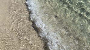 Una playa con aguas claras y poco profundas y una orilla arenosa.