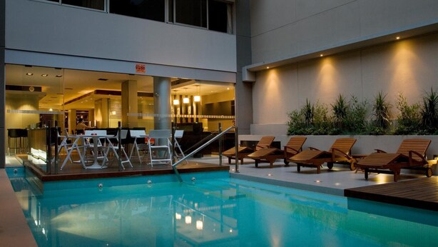 A pool area with lounge chairs and a bar area visible through glass doors.