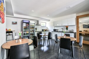 Una cocina moderna con armarios blancos, un refrigerador y un comedor con sillas negras y una mesa de madera.
