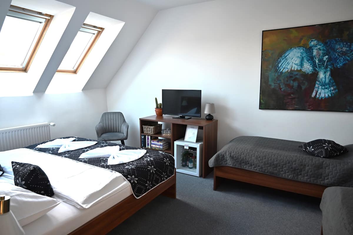 A bedroom with a bed, a desk, a chair, a television, and a painting.