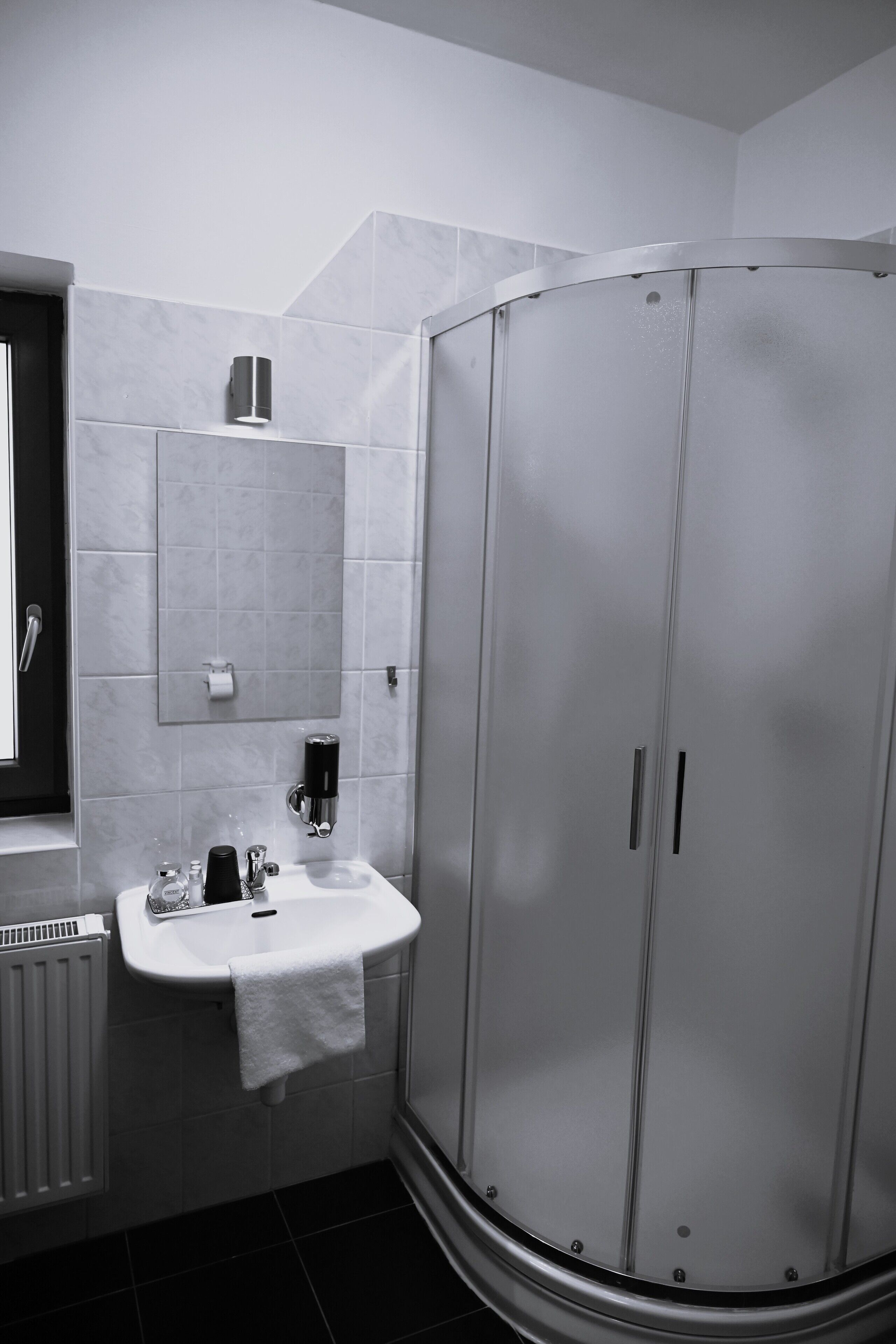 Une salle de bain avec un lavabo blanc, un miroir, une serviette, une douche et des toilettes.