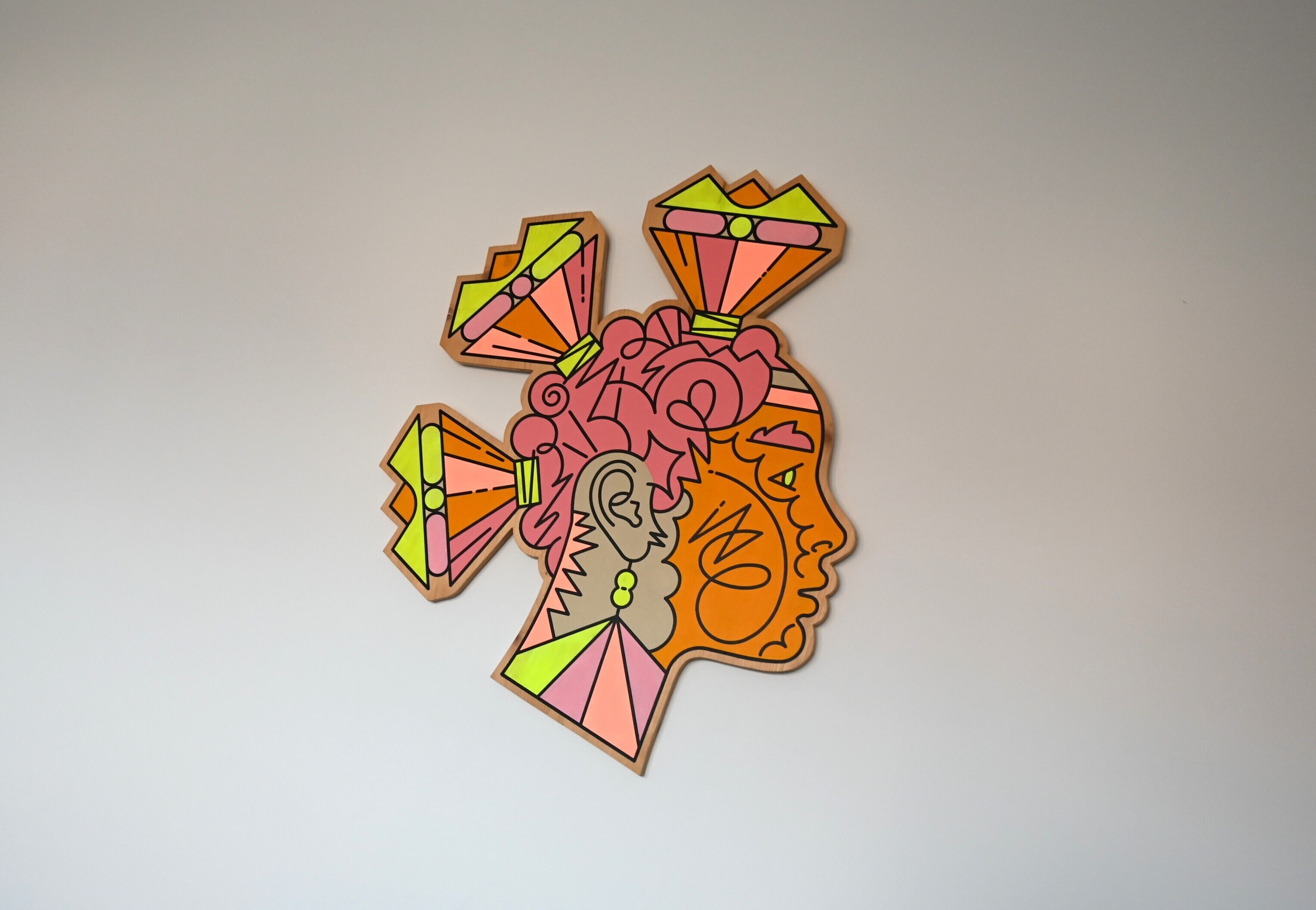 Een kleurrijk abstract kunstwerk op een effen muur.