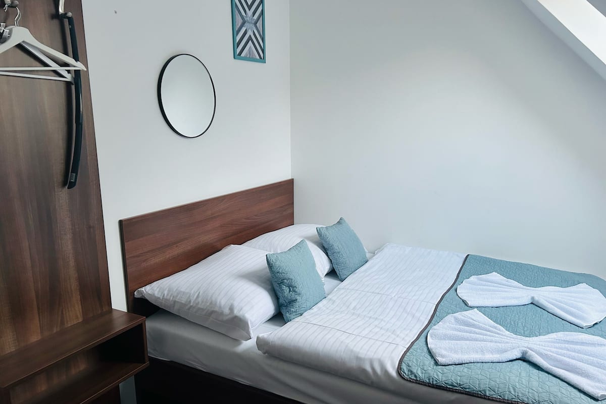 A neatly made bed with white and blue bedding, a wooden headboard, and a small bedside table.