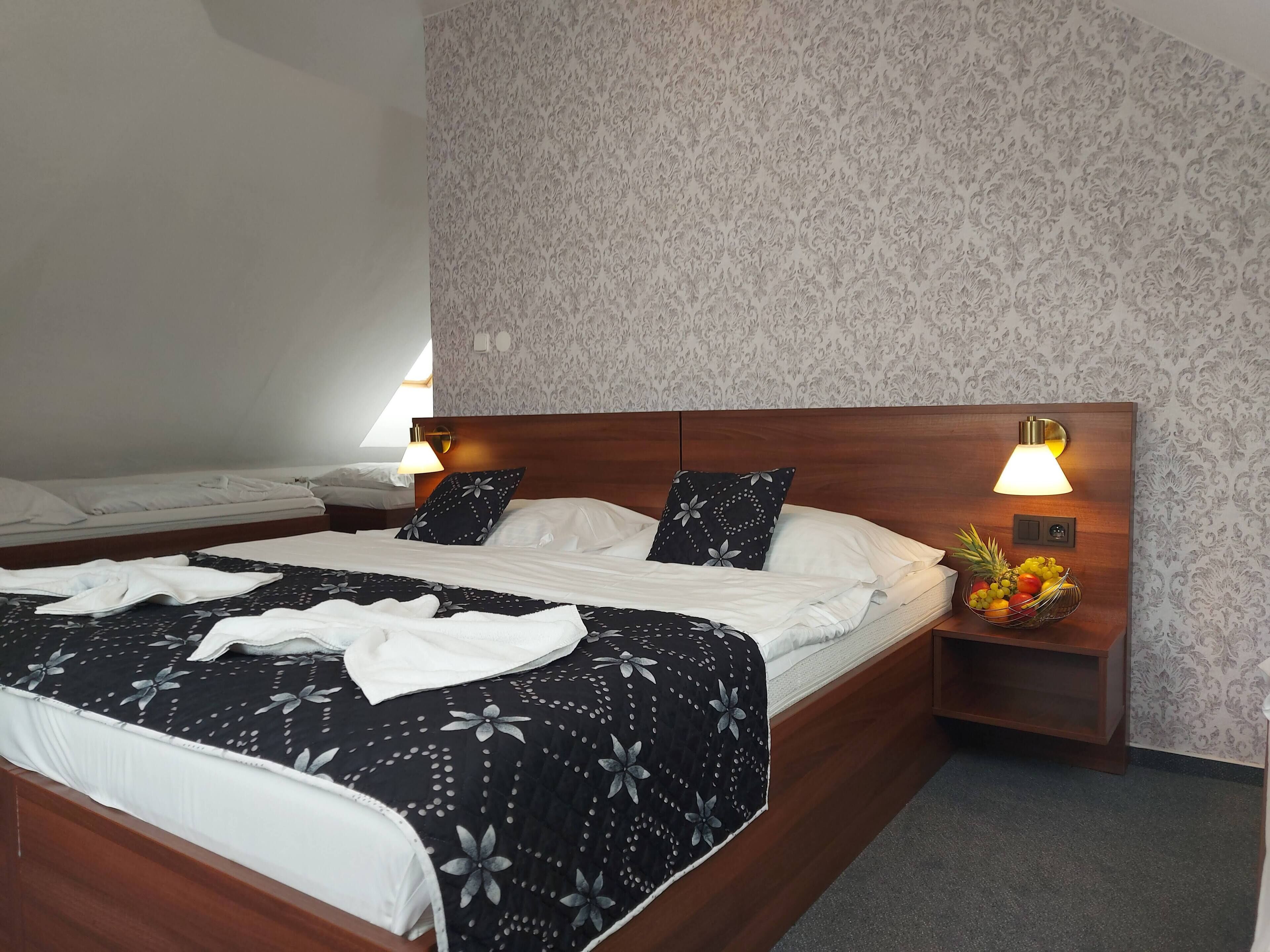 A hotel room with a large bed, two bedside tables, and a wall-mounted lamp.