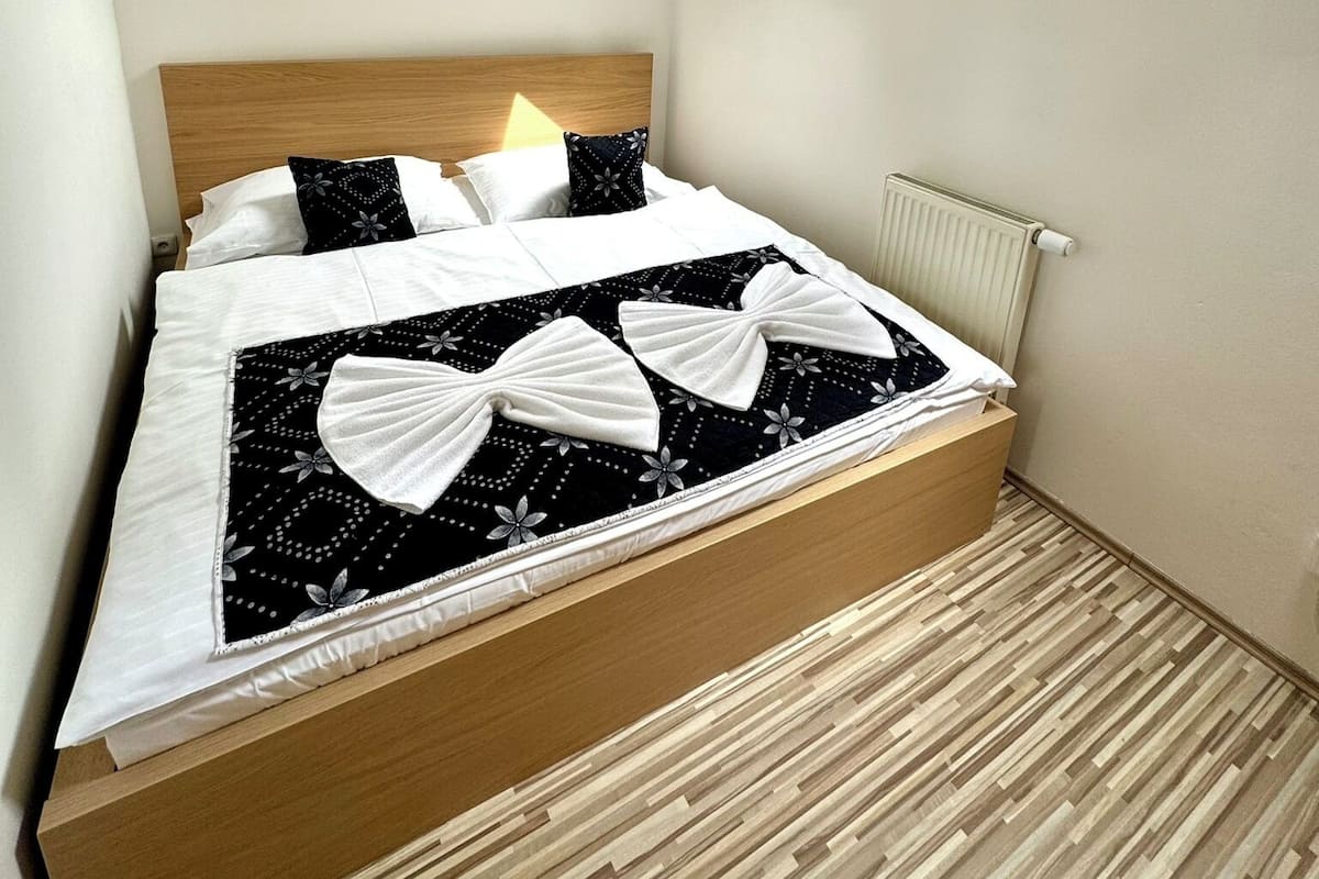 A bedroom with a sloped ceiling, a skylight, a bed with a black and white floral bedspread, and a wooden headboard.