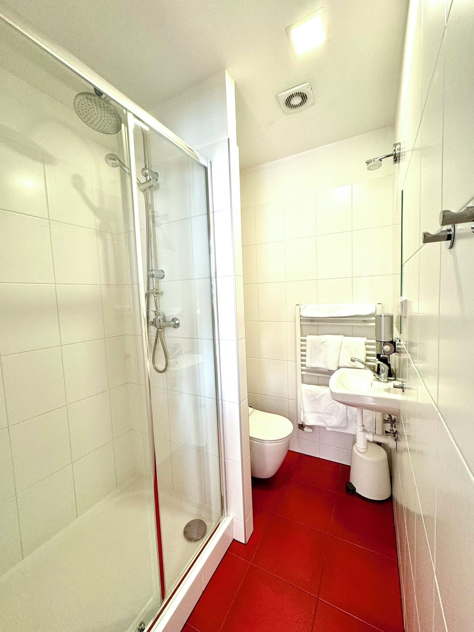 A modern bathroom with a glass shower enclosure, a white toilet, and a sink with a mirror.