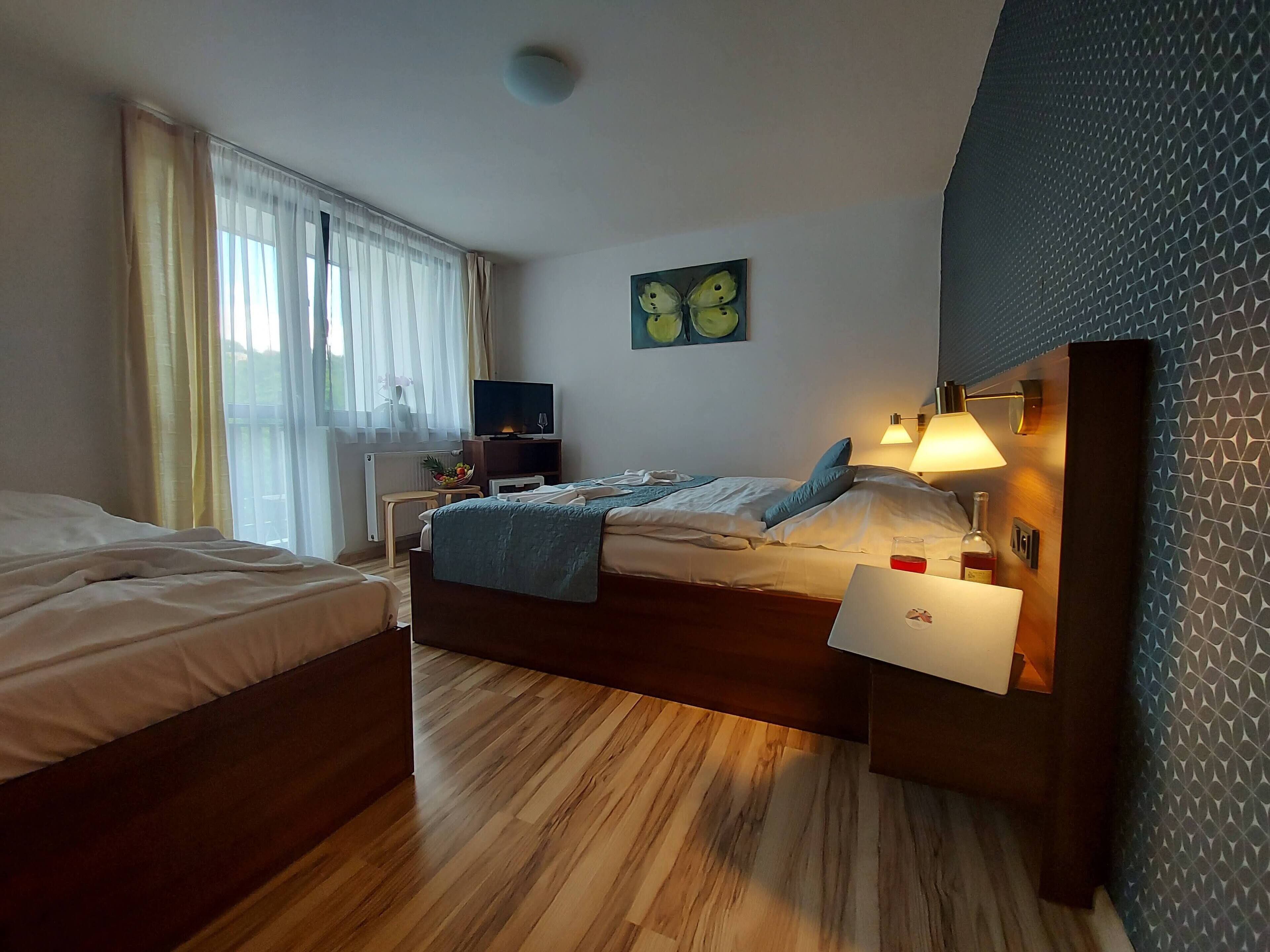 A hotel room with a bed, bedside table, lamp, and a painting on the wall.