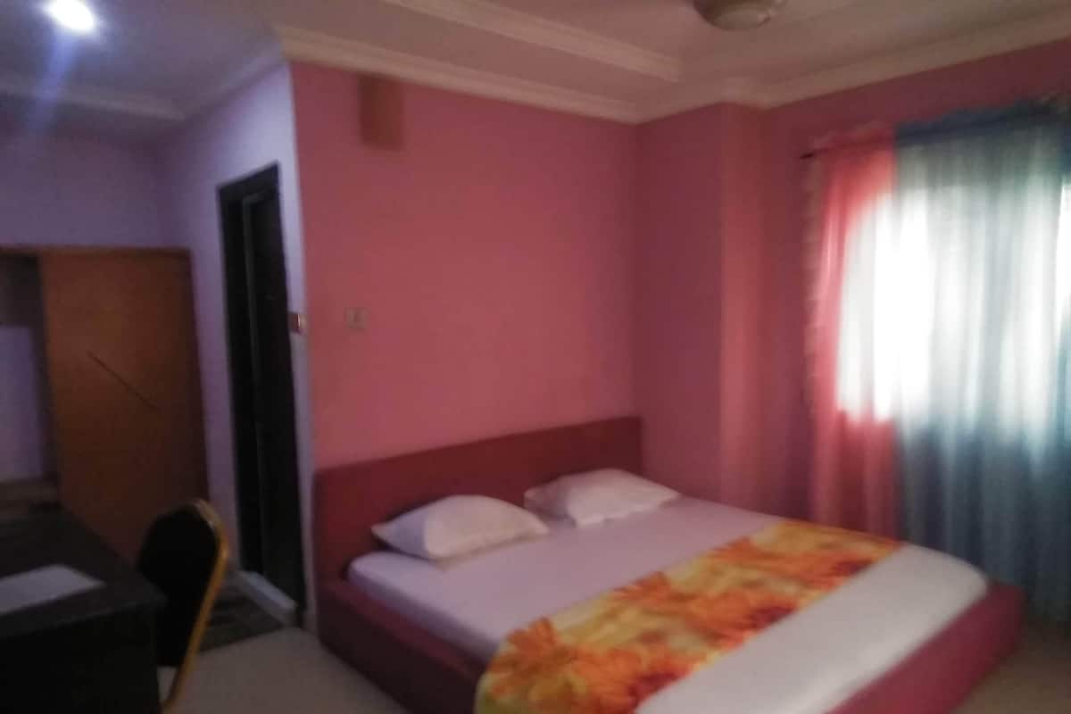 A bedroom with a bed, a desk, and a chair.