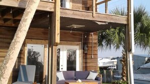 Une maison en bois à deux étages, dotée d’un balcon, d’un ventilateur de plafond et d’un patio avec une table et des chaises.