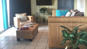 Un salon avec un canapé, des fauteuils, une table basse et un téléviseur.