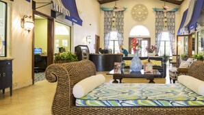A spacious lobby with a large woven sofa, a reception desk, and a ceiling fan.