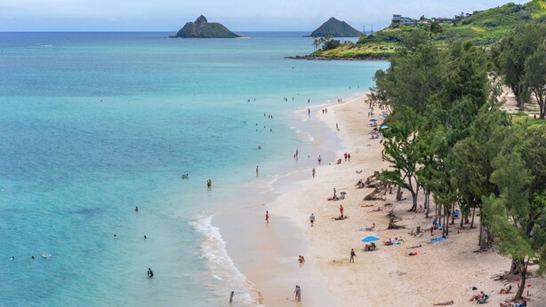 A beach with clear turquoise water, a sandy shore, and a few people. - Relax at Kapakai Cottage – 2-Bedroom Comfort with Full Kitchen & W/D (Kailua)