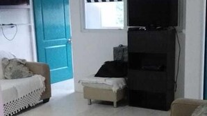 A living room with a beige sofa, a television, a ceiling fan, and a blue door. - Apartamento en Altos de Santa Maria Condado del Rey, Imajo (San Miguelito)