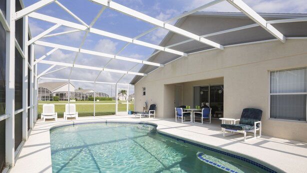 Une piscine avec un patio couvert, du mobilier d’extérieur et une vue sur le quartier.
