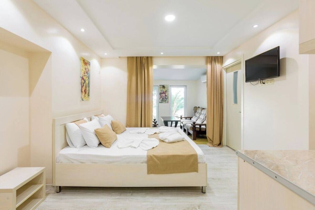 A modern hotel room with a bed, a TV, and a desk area.